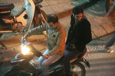 Một khách tây đeo Ipod nghe nhạc đang nhờ xe ôm chở đi tìm quán thích hợp để vào ngồi