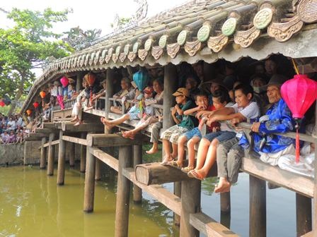 Thân thương phiên chợ quê bên cầu ngói Thanh Toàn - 8 Người già, trẻ nhỏ ngồi vắt chân đung đưa trên cầu ngói Thanh Toàn xem đua ghe hội