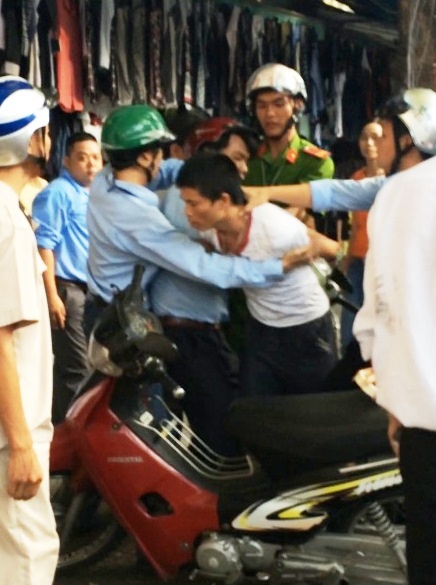 Dân tố cán bộ đô thị xông vào quầy thu quần áo kiểu...cưỡng đoạt tài sản - 2 Hình ảnh ông Phú bị cán bộ đô thị bẻ Ŵay, nắm cổ (ảnh cắt từ clip người dân cung cấp)