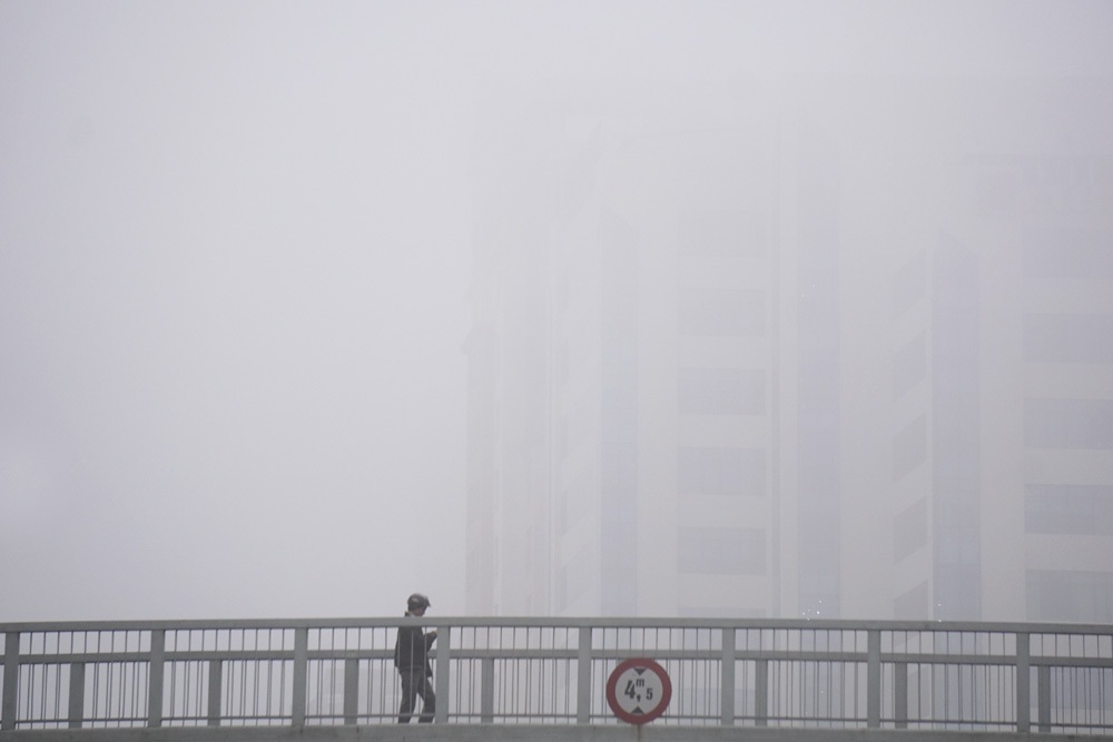 Sương mù dày đặc bao phủ Hà Nội - 1 Tầm nhìn hạn chế, các cây cầu vượt cho người đi bộ trở nên xa mờ đối với người đi dưới đường.