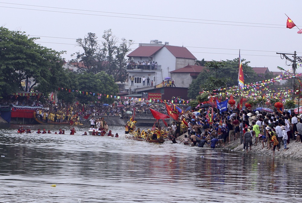 Mũi thuyền của thôn 1 đã chèo hẳn lên thân thuyền thôn 2 (áo vàng).