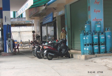 Nữ nhân viên bán xăng sử dụng điện thoại (Ảnh: Hồng Long)