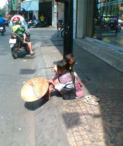 Hai chị em bị bắt ngồi giữa trời nắng chang chang để ngửa nón xin tiền người đi đường