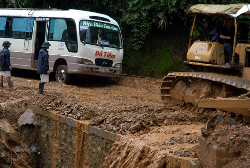 Xe ủi kéo xe khách vượt qua vũng lầy và khu vực sạt lở để giải tỏa ách tắc.