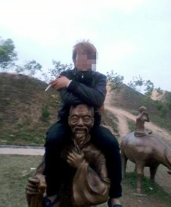 Người thanh niên hồ hởi ngồi trên vai tượng chụp ảnh