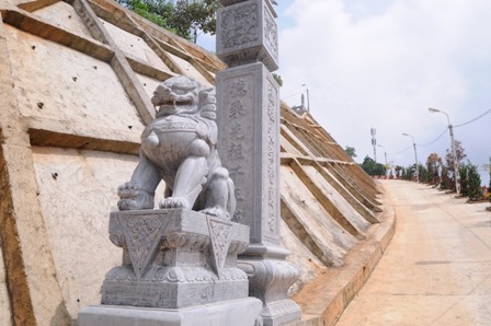 Đường cho ô tô dẫn lên khu lăng mộ với hàng cột điện cao áp và cây xanh xen kẽ