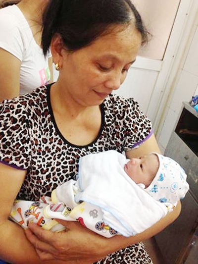 Bà Thái Thị Tuyến - mẹ trung úy Nguyễn Văn Hưng hạnh phúc bế cháu nội trên tay.