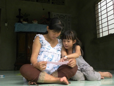 Hai mẹ con đang coi lại tờ giấy ra viện
