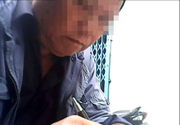 “Chiêu bài”… mang bầu giả! - 1 Ông Hai đang viết giấy thỏa thuận cho cháu. Ảnh: TRẦN NGỌC