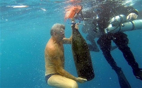 Ông đang nâng hũ rượu lên mặt nước