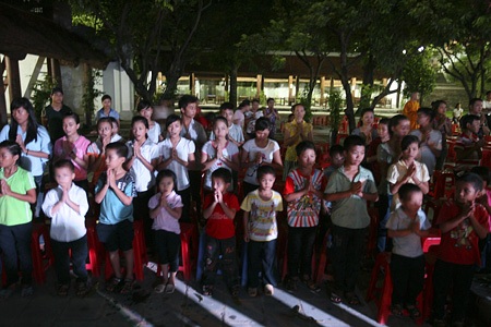 Những đứa trẻ chắp tay thành kính khi bắt đầu nghi lễ cài hoa lên ngực.