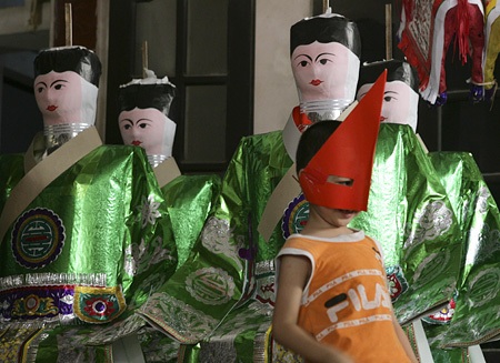 Một em bé đang chơi đùa bên những hình nhân.