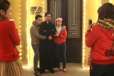Đêm Noel ở Nhà thờ lớn - 8 Các bạn trẻ đang chụp ảnh lưu niệm cùng một Thầy của nhà thờ.