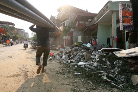 Tan hoang Mường Khương - 19 Một người dân đang bê ống nước bên cạnh đống đổ nát hiện diện khắp thị trấn.