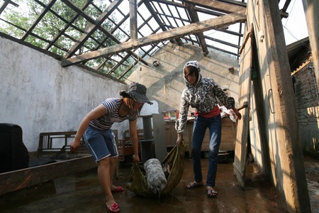 Tan hoang Mường Khương - 20 Một người dân đang bê ống nước bên cạnh đống đổ nát hiện diện khắp thị trấn.