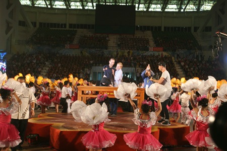 Nick được cộng sự đưa ra sân khấu trong vòng vây các em nhỏ Việt Nam.