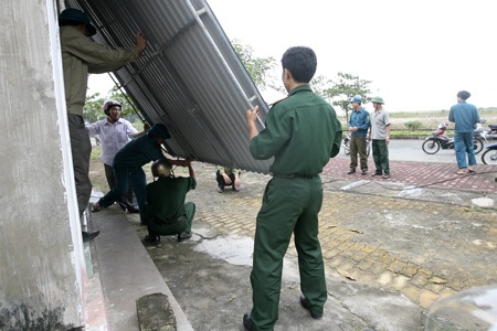 Thị xã Cửa Lò căng người chờ bão Haiyan - 10 Lực lượng chức năng đang giúp một gia đình bịt cửa ra vào của một ngôi nhà.