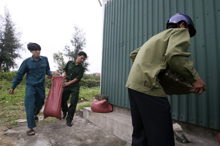Thị xã Cửa Lò căng người chờ bão Haiyan - 11 Lực lượng chức năng đang giúp một gia đình bịt cửa ra vào của một ngôi nhà.