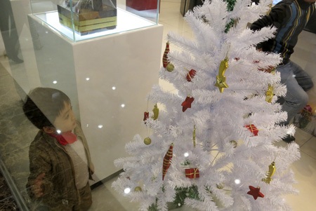 Một Hà Nội rất khác trước đêm Noel - 12 Một em nhỏ đang nhìn ngắm cây thông mùa đông với các gói quà