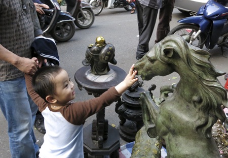 Chú bé thích thú với con ngựa bằng đồng.