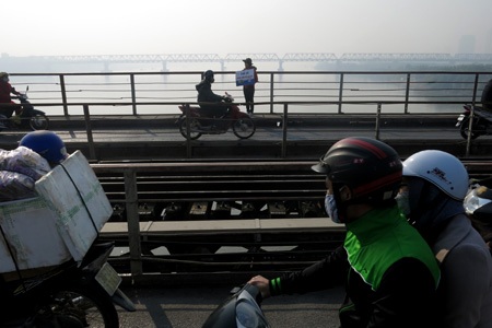 Một nữ sinh viên kiên trì đứng xin rác giữa trời nắng trên cầu.