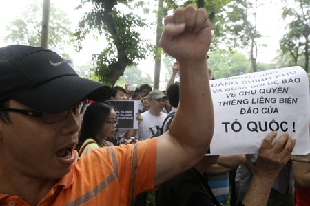 Một thanh niên trong đoàn tuần hành với lá cờ Đảng trước cổng ĐSQ Trung Quốc.