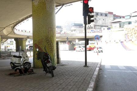 “Màn trời chiếu đất” giữa trưa hè 39 độ C - 2 Một người xe ôm tháo bớt quần áo, lấy gầm cầu làm chỗ ngủ.