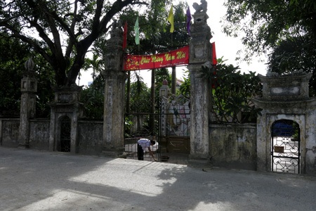 Cổng làng cổ Cự Khê với chiếc đồng hồ điện tử được treo tùy tiện phía trên lỗ hổng sát mái.