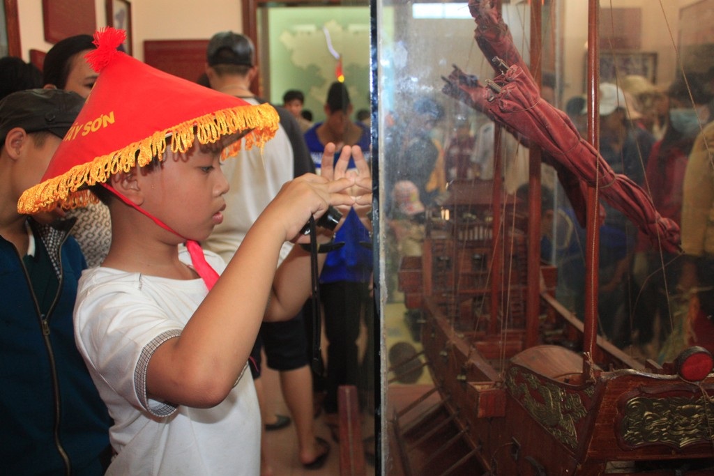 Một em nhỏ chụp hình chiếc thuyền chiến mà nghĩa quân nhà Tây Sơn đánh tan quân xâm lược