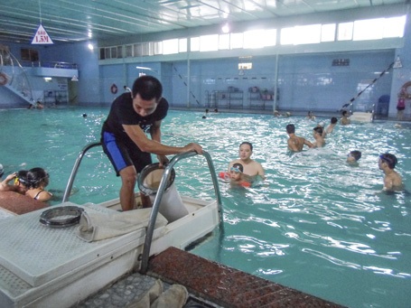  Nhân viên Trịnh Văn Việt đang làm vệ sinh bể bơi.