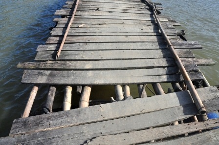 Trên mặt cầu nhiều tấm ván gỗ bị rớt, bên dưới nhiều thùng phuy cũng bị mất