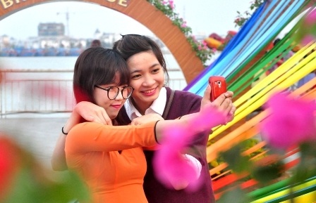 Các bạn trẻ chụp hình bên đường hoa Xuân