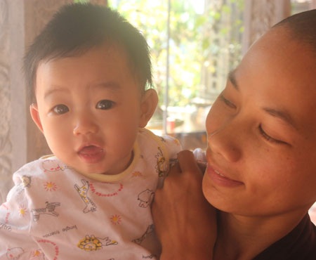nụ cười đáng yêu của bé Nhân Tịnh khi được sư thầy Thích Đàm Thảo bồng bế