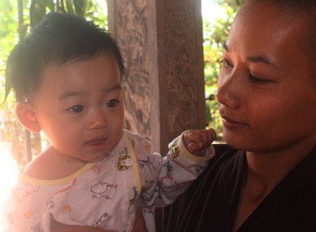 nụ cười đáng yêu của bé Nhân Tịnh khi được sư thầy Thích Đàm Thảo bồng bế