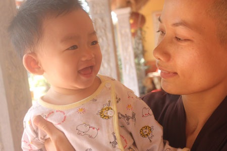 nụ cười đáng yêu của bé Nhân Tịnh khi được sư thầy Thích Đàm Thảo bồng bế