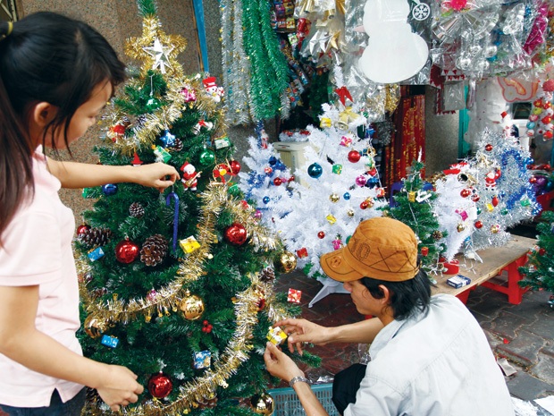 Nhân viên trang trí cây thông cho khách tại một cửa hàng trên đường Hải Thượng Lãn Ông.