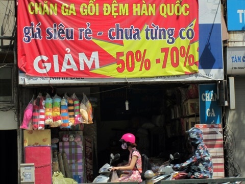 Cửa hiệu bán chăn, ga, gối đệm với băng rôn cam kết rẻ nhất thị trường.