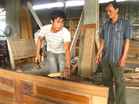 Thành ông chủ từ 300.000 đồng - 1 Ông Nhương (phải) giám sát công nhân làm việc trong xưởng mộc của gia đình.