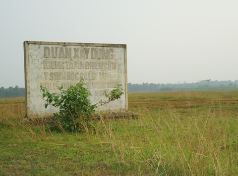 Tấm bia quy hoạch nằm giữa đồng cỏ, dự án Trung tâm nghiên cứu Y sinh học quốc tế.