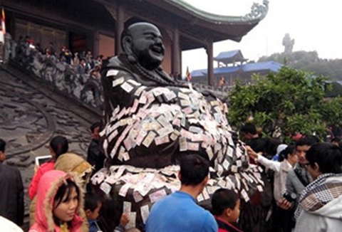 Hình ảnh phản cảm khi đặt tiền lẻ lên tượng phật ( Ảnh: Báo Văn hóa)