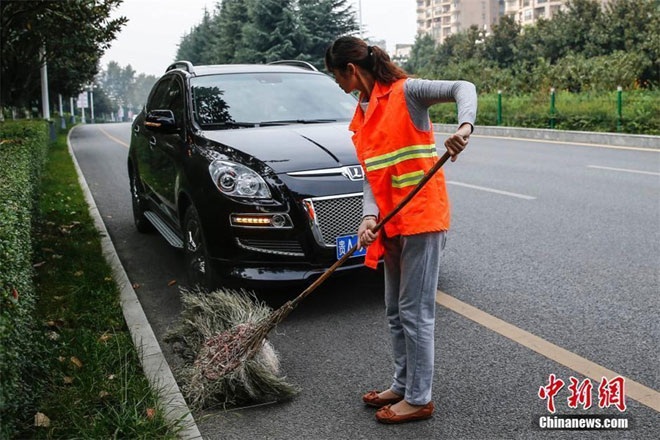 Lạ lẫm hàng trăm triệu phú chọn nghề quét rác - 4 Wang Demin, 55 tuổi, quét dọn đường phố bên cạnh xế sang của cô. Cô xài ôtô riêng đi làm đã 10 năm.