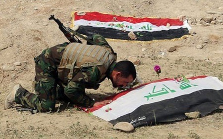 Kinh hoàng phát hiện 8 hố chôn tập thể với 1.700 xác chết ở Tikrit - 1 Một người lính Iraq kính cẩn trước sự hy sinh của đồng đội. (Ảnh: