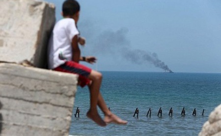 Một cậu bé theo dõi vụ cháy tàu từ xa.