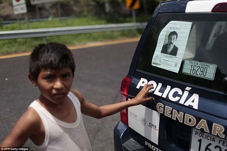 "Quyền lực động trời" trong tù của trùm ma túy Mexico vừa đào tẩu - 6 Một cậu bé Mexico đứng sau chiếc xe cảnh sát có dán yết thị truy nã trùm El Chapo (Nguồn: