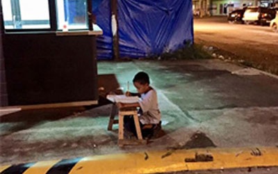 Xúc động cậu bé vô gia cư học bài dưới ánh đèn hắt từ nhà hàng - 1 Xót xa cậu bé ngồi học dưới ánh đèn le lói hắt ra từ phía nhà hàng.