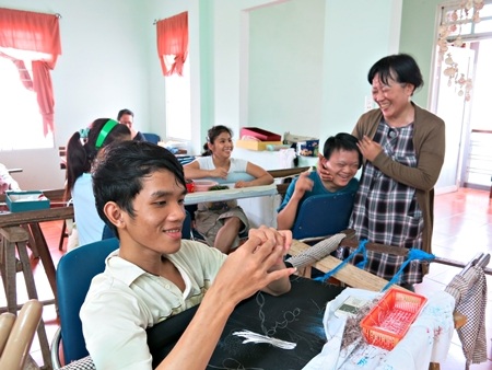 Chị Liền bên “các con” ở cơ sở dạy nghề tranh thêu cho trẻ khuyết tật Thanh Ngọc Minh