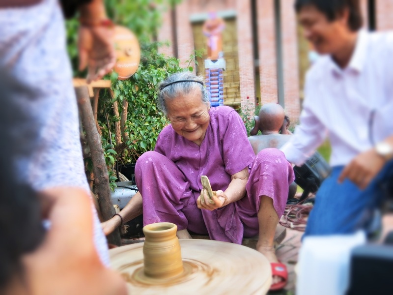 Nghệ nhân Nguyễn Thị Được chuốt sản phẩm gốm đầu tiên ở Công viên đất nung vừa hoàn tất giữa làng