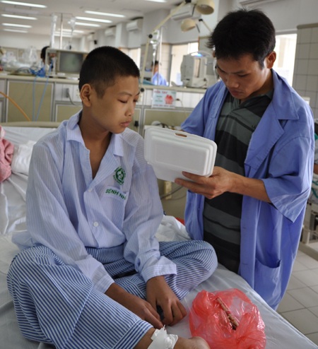 Chân tay không hoạt động được nên cậu bé Đoàn phải nhờ bố đút cơm.