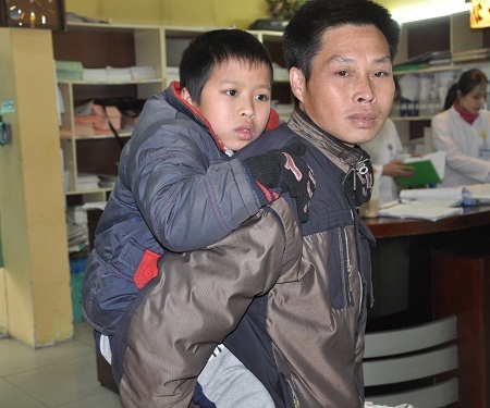 Chưa thể đi lại được nên Minh được bố cõng lên viện khám bệnh.