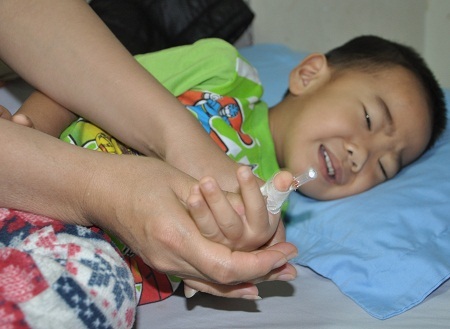 Vừa truyền xong chai hóa chất, bé Thế Anh đau khắp mình mẩy nên mẹ phải liên tục ngồi nắn bóp.